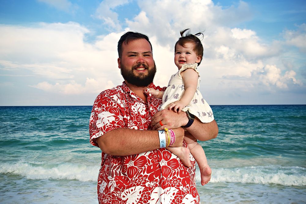 Dad holding his daughter by the ocean
