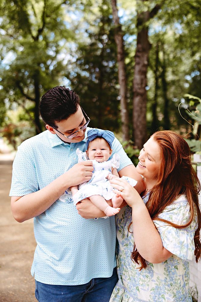 Young family with their baby girl under the trees